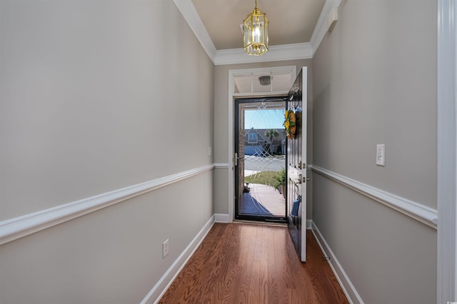 doorway to outside with baseboards, dark wood-type flooring, a chandelier, and crown molding