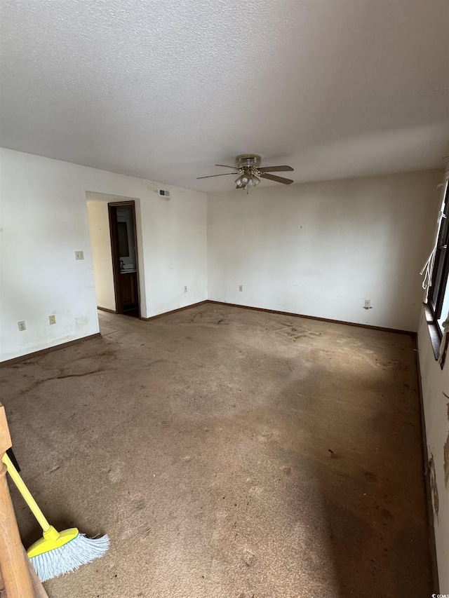 unfurnished room featuring baseboards, visible vents, a textured ceiling, and a ceiling fan