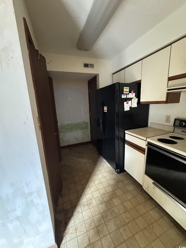 kitchen featuring visible vents, extractor fan, electric range oven, freestanding refrigerator, and white cabinets