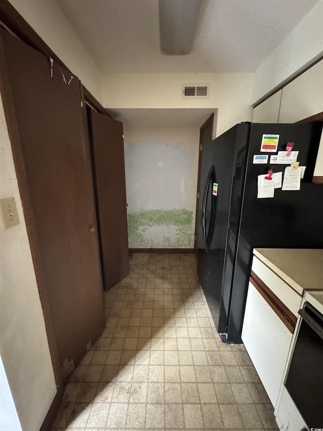 kitchen featuring visible vents, light floors, light countertops, freestanding refrigerator, and range