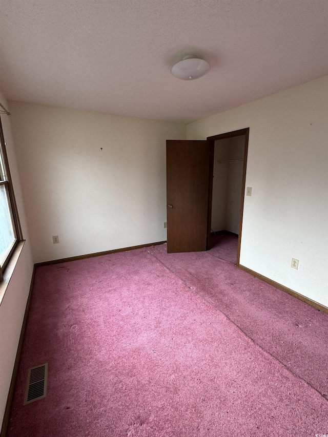 carpeted empty room with baseboards, visible vents, and a textured ceiling