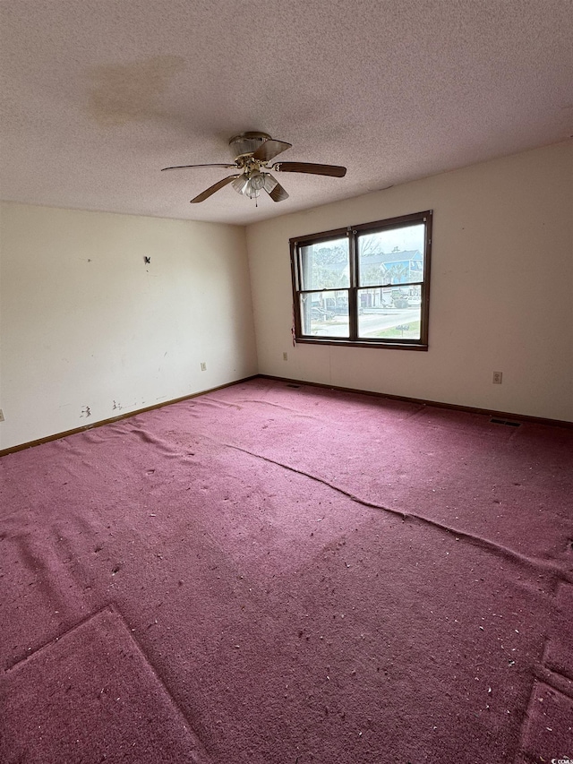 empty room with carpet flooring, a textured ceiling, and baseboards