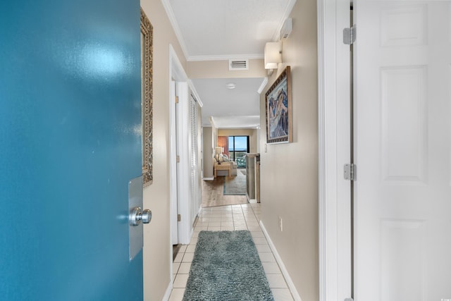 hall featuring light tile patterned floors, visible vents, crown molding, and baseboards