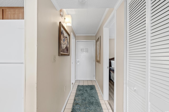 hallway with ornamental molding, light tile patterned floors, and a textured ceiling
