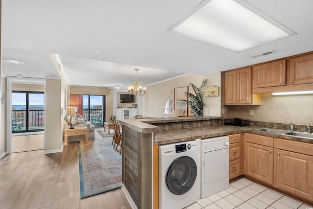 kitchen with dark countertops, a notable chandelier, a peninsula, and a sink