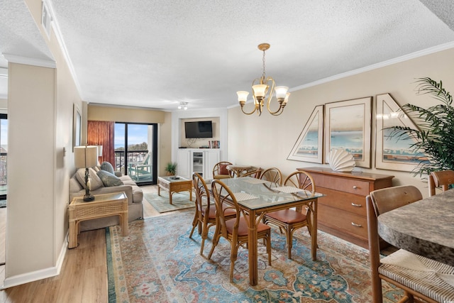 dining room featuring a textured ceiling, crown molding, light wood finished floors, baseboards, and a chandelier