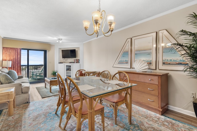 dining area featuring light wood-type flooring, beverage cooler, an inviting chandelier, crown molding, and baseboards