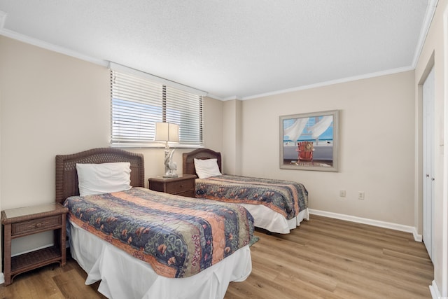 bedroom with a textured ceiling, crown molding, baseboards, and wood finished floors