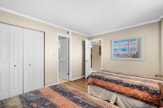 bedroom featuring visible vents, crown molding, wood finished floors, a closet, and a textured ceiling