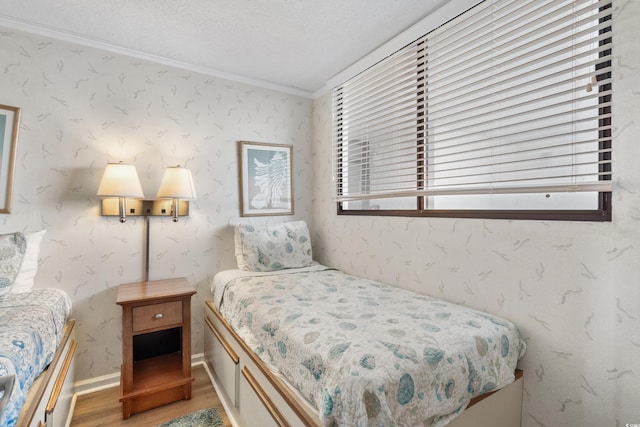 bedroom featuring wallpapered walls, crown molding, and wood finished floors
