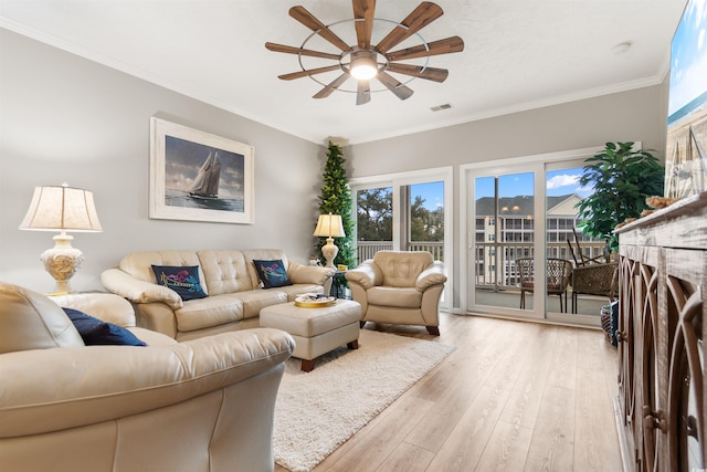 living area featuring light wood-style flooring, a ceiling fan, visible vents, and ornamental molding