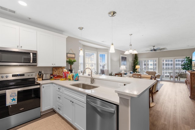 kitchen featuring visible vents, a sink, open floor plan, stainless steel appliances, and a peninsula