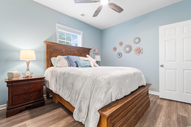 bedroom featuring visible vents, baseboards, wood finished floors, and a ceiling fan