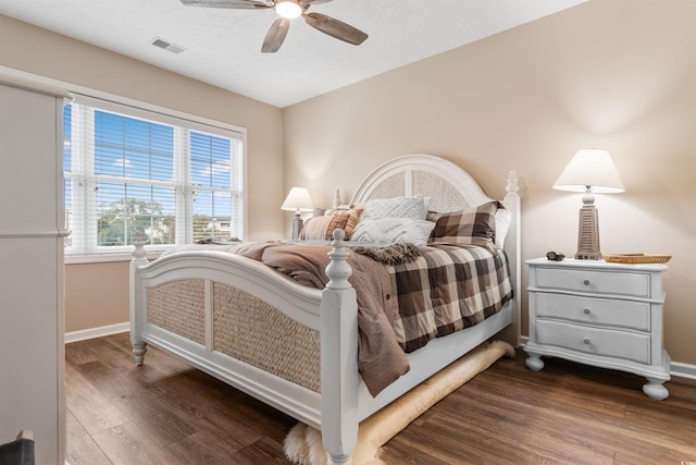 bedroom featuring visible vents, baseboards, dark wood finished floors, and a ceiling fan