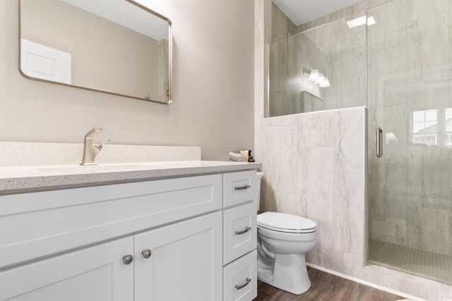 bathroom featuring vanity, a shower stall, toilet, and wood finished floors