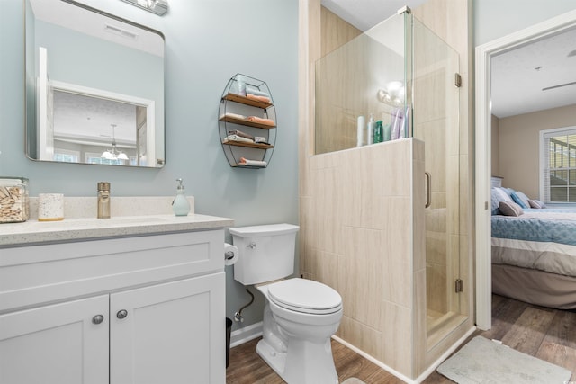 ensuite bathroom with a stall shower, connected bathroom, toilet, and wood finished floors