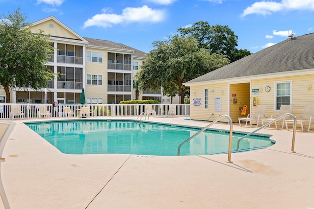 community pool with a patio and fence