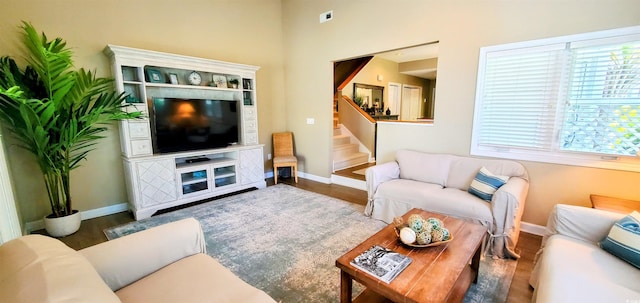 living room with baseboards, stairs, and wood finished floors