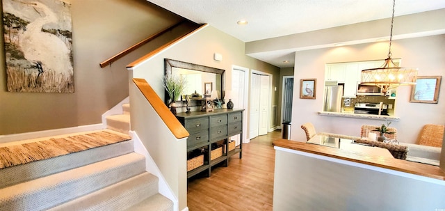 stairs with an inviting chandelier, baseboards, recessed lighting, and wood finished floors