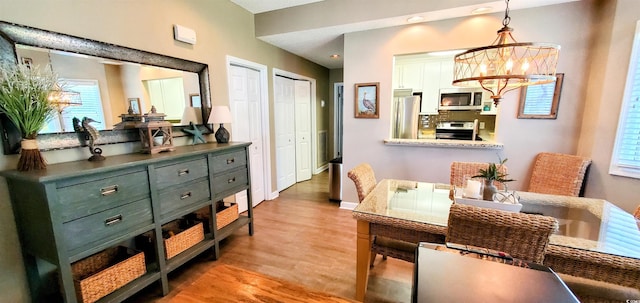 dining space featuring an inviting chandelier, baseboards, plenty of natural light, and light wood-style flooring