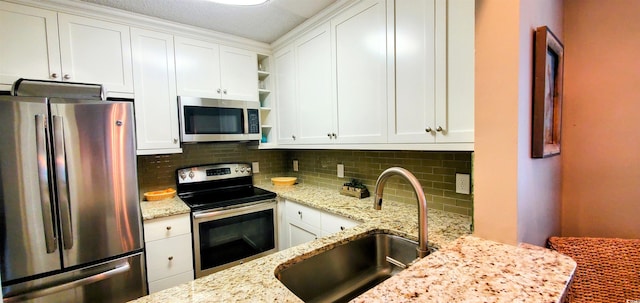 kitchen with a sink, decorative backsplash, white cabinetry, and stainless steel appliances