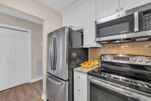kitchen featuring backsplash, stainless steel appliances, visible vents, and white cabinetry