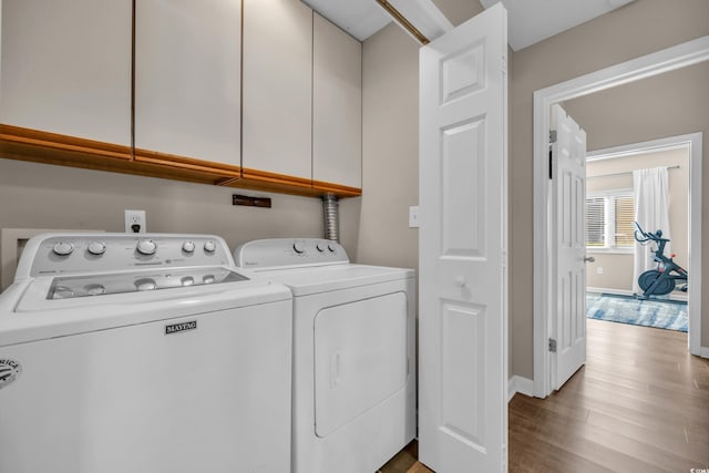 laundry room featuring baseboards, cabinet space, wood finished floors, and washing machine and clothes dryer