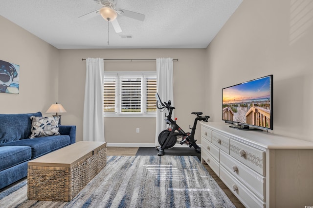 interior space featuring visible vents, wood finished floors, baseboards, a textured ceiling, and a ceiling fan