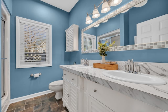 full bath featuring an enclosed shower, baseboards, stone finish flooring, and a sink