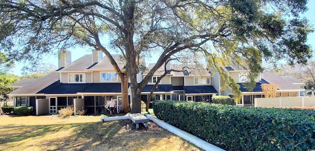 back of house with a sunroom and a chimney