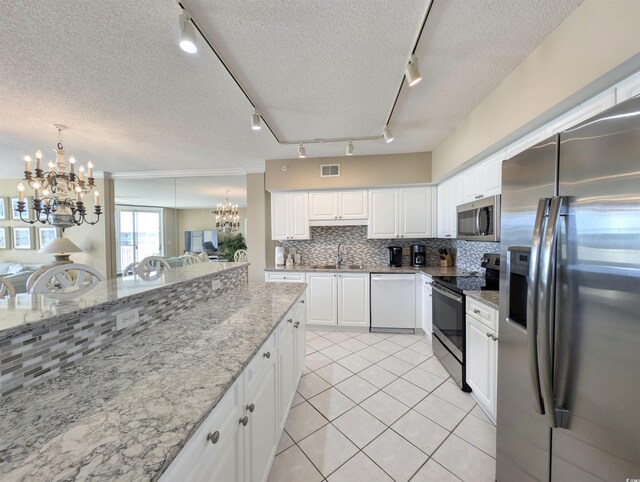 kitchen featuring visible vents, a notable chandelier, a sink, stainless steel appliances, and decorative backsplash