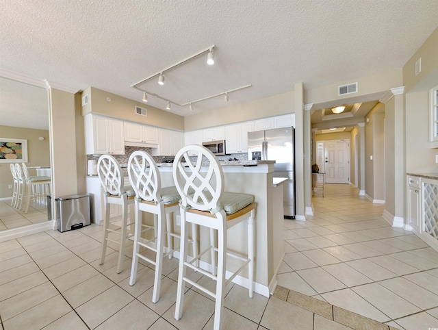 kitchen featuring tasteful backsplash, light tile patterned flooring, visible vents, and appliances with stainless steel finishes