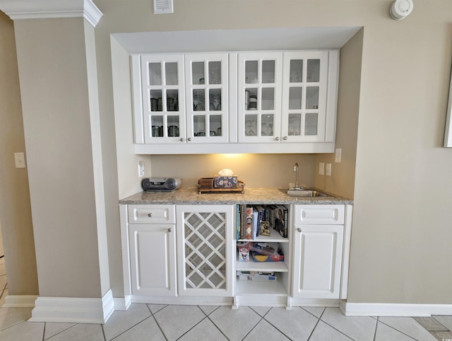 bar with wet bar, light tile patterned flooring, baseboards, and a sink