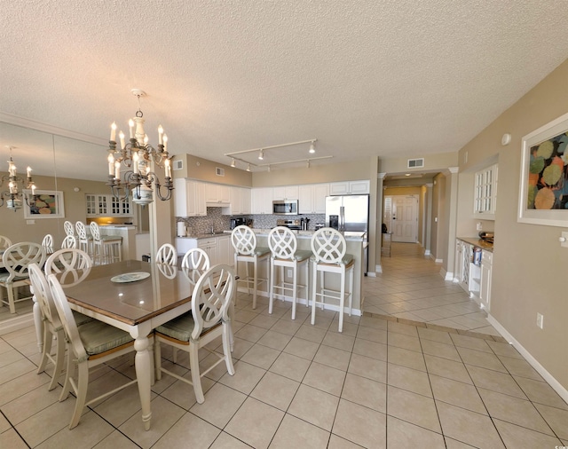 dining space with light tile patterned flooring, a notable chandelier, a textured ceiling, and visible vents