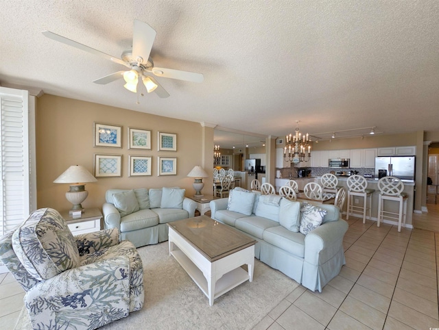 living area with light tile patterned floors, ceiling fan with notable chandelier, and a textured ceiling