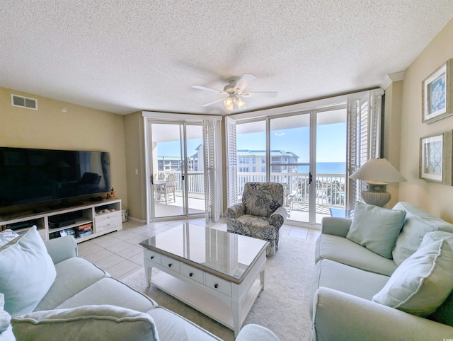 living area featuring light tile patterned floors, visible vents, a ceiling fan, and a wealth of natural light