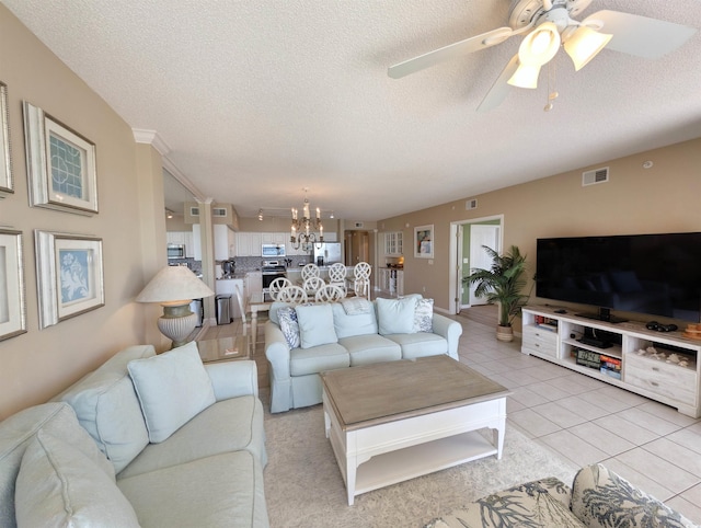 living area featuring light tile patterned floors, ceiling fan with notable chandelier, visible vents, and a textured ceiling