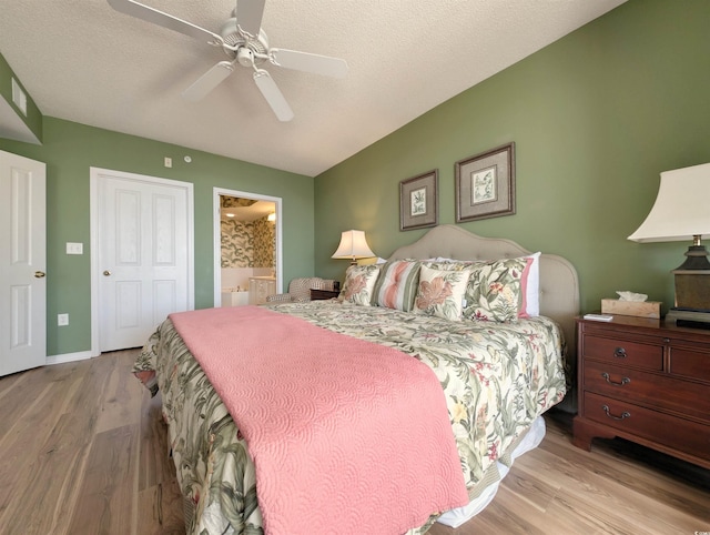 bedroom with connected bathroom, a textured ceiling, baseboards, and wood finished floors