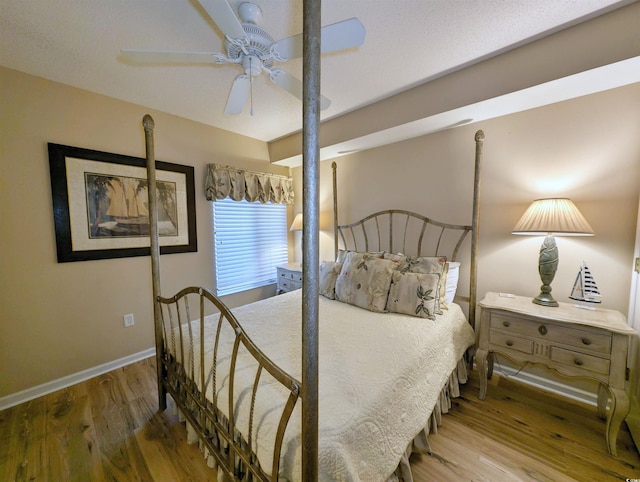 bedroom with a ceiling fan, baseboards, and wood finished floors