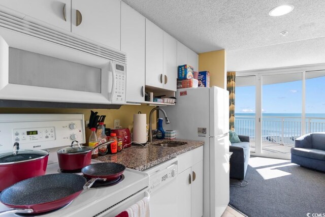 300 N Ocean Blvd Unit 731, North Myrtle Beach, SC 29582 - kitchen featuring white appliances, a sink, white cabinets, a water view, and a textured ceiling