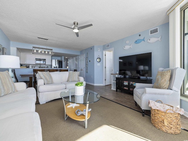 living area featuring visible vents, a textured ceiling, and wood finished floors