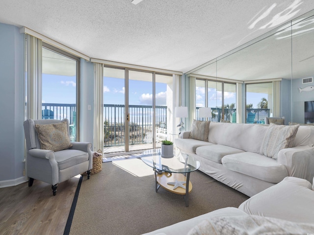 living area with floor to ceiling windows, a textured ceiling, a healthy amount of sunlight, and wood finished floors
