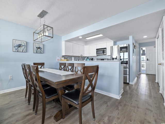 dining room with a textured ceiling, baseboards, and wood finished floors