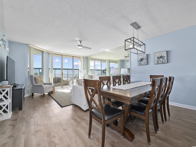 dining space with baseboards, floor to ceiling windows, wood finished floors, a textured ceiling, and a ceiling fan