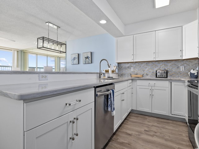 kitchen with stainless steel dishwasher, light countertops, tasteful backsplash, and a sink