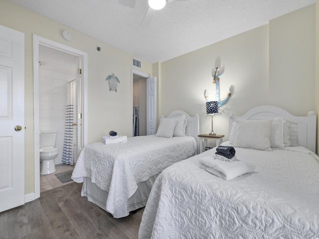 bedroom featuring visible vents, ensuite bathroom, a textured ceiling, ceiling fan, and dark wood-style flooring