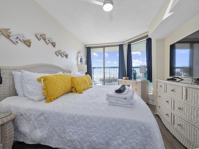 bedroom featuring a wall of windows, access to exterior, dark wood-style flooring, and a textured ceiling