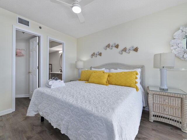 bedroom featuring wood finished floors, visible vents, baseboards, ceiling fan, and a walk in closet