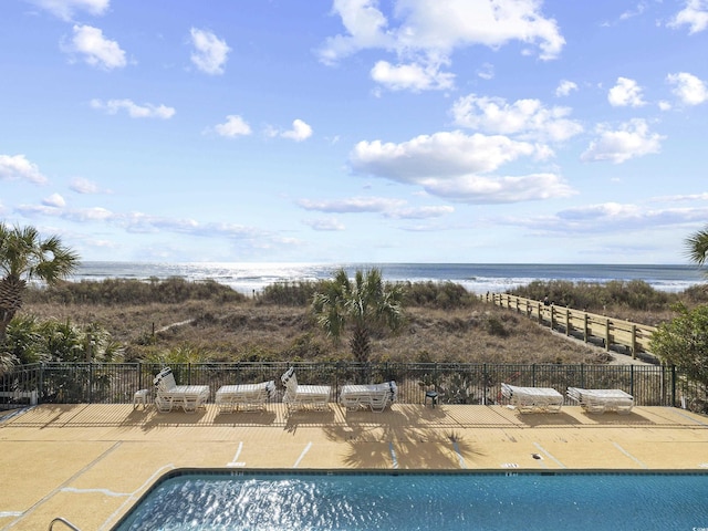 community pool with a patio area, a water view, and fence