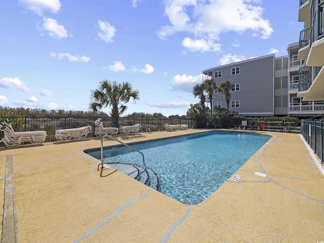 pool with a patio area and fence